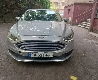 Vista frontale di un noleggio Ford Fusion Sedan all'aeroporto di Tbilisi, Georgia ✓ Auto #7129. ✓ Cambio Automatico TM ✓ 0 recensioni.