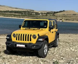 Vista frontale di un noleggio Jeep Wrangler a Tbilisi, Georgia ✓ Auto #10830. ✓ Cambio Automatico TM ✓ 0 recensioni.